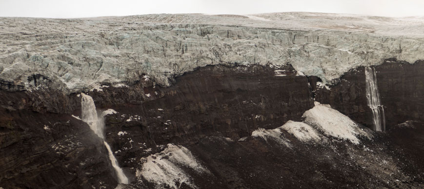 Wasserfälle stürzen über einen Felssturz vom oberen Bereich des Holdujökull auf die unteren Eisfelder des Gletschers